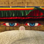 A tight close-up shot of the painted blue wisdom eyes of Buddha on the golden spire of Boudhanath Stupa.