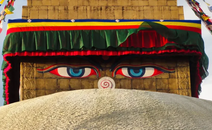 A tight close-up shot of the painted blue wisdom eyes of Buddha on the golden spire of Boudhanath Stupa.
