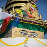 A close-up shot of the iconic wisdom eyes of Buddha painted on the golden spire of Swayambhunath Stupa