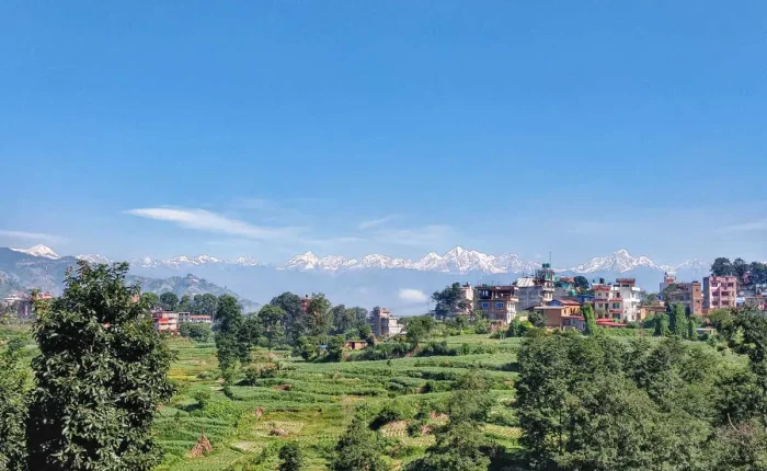 A spectacular panoramic view of the snow-capped Langtang Himalayan range stretching across a clear blue sky over the green terraced valleys of Dhulikhel.