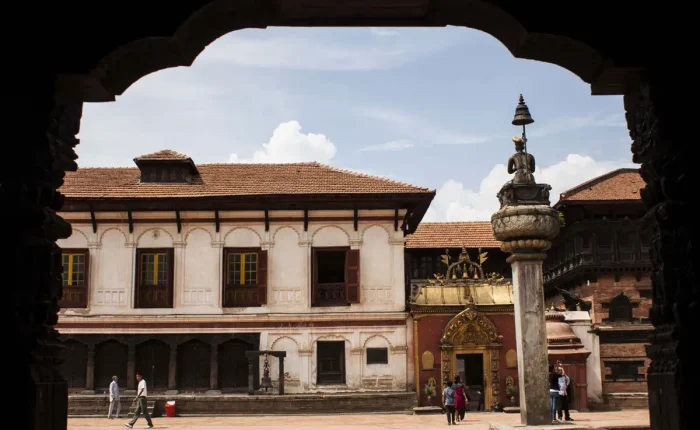 Tourists exploring the courtyard of the 55 Window Palace with a view of the famous Golden Gate and King Bhupatindra Malla monument.