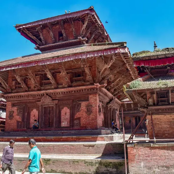 The multi-tiered wooden and brick structure of the Jagannath Temple against a bright blue sky at Kathmandu Durbar Square.