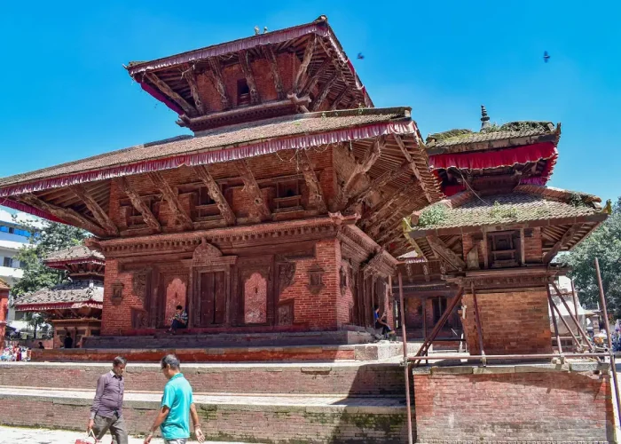 The multi-tiered wooden and brick structure of the Jagannath Temple against a bright blue sky at Kathmandu Durbar Square.