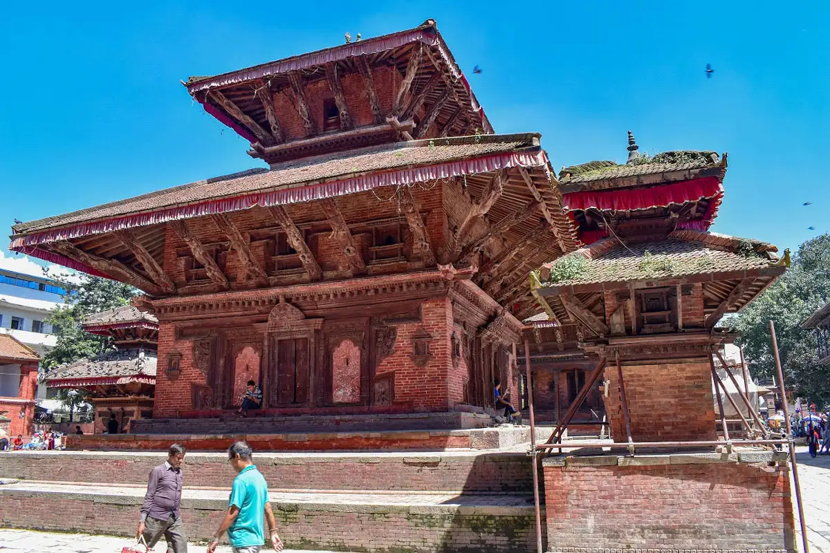 The multi-tiered wooden and brick structure of the Jagannath Temple against a bright blue sky at Kathmandu Durbar Square.