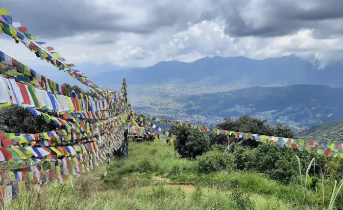 Thousands of colorful Buddhist prayer flags stretched across a grassy hilltop ridge on the Nagarjun Jamacho day hike route.