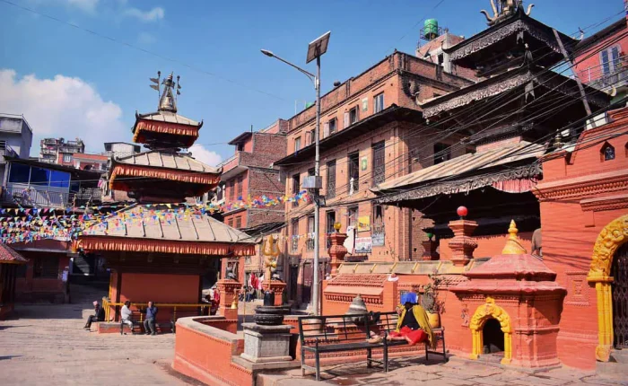 The historical three-tiered Narayan Temple courtyard in Dhulikhel old town, featuring red brick architecture and gold accents under a clear sky.