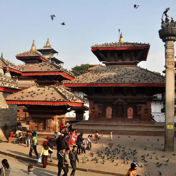 Tourists and pigeons gathered around the historic pagoda temples and the Garuda pillar at Kathmandu Durbar Square.