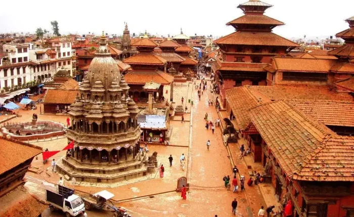 An elevated high-angle view looking down at the stone Krishna Mandir temple and red-tiled pagoda roofs of Patan Durbar Square.