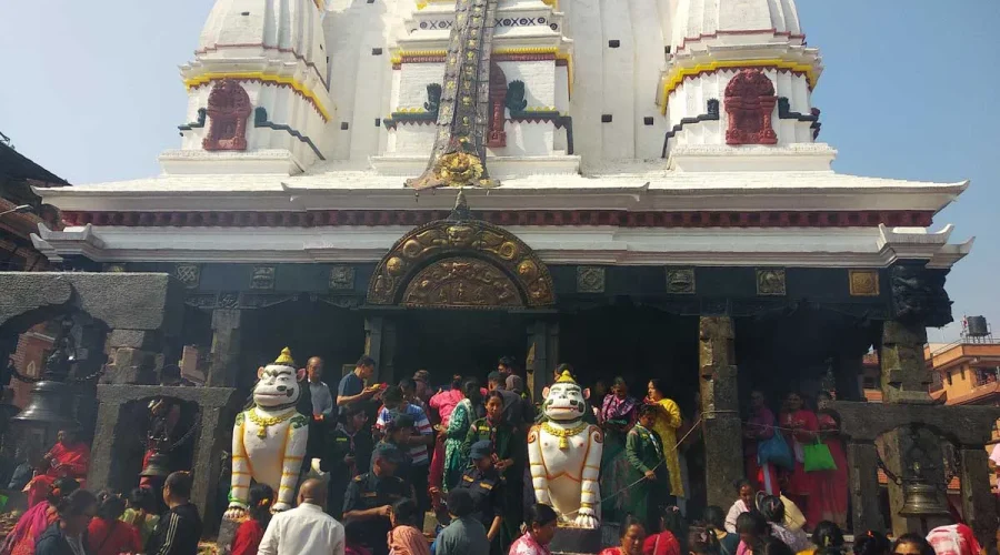 Devotees and travelers gathered at the entrance of the Rato Machindranath Temple in Bungmati, featuring white lion stone guardians at the steps.