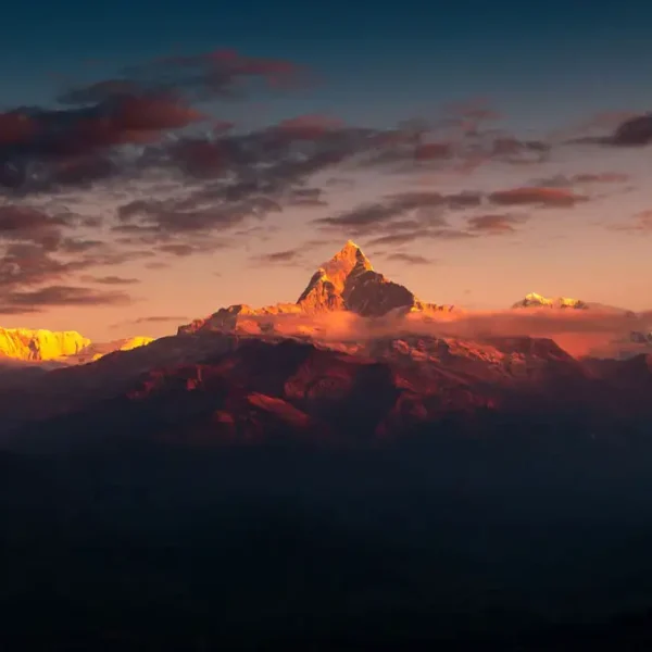 A breathtaking golden sunrise illuminating Mount Machapuchare and the Annapurna range with orange light, a popular view from Sarangkot.