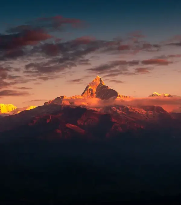 A breathtaking golden sunrise illuminating Mount Machapuchare and the Annapurna range with orange light, a popular view from Sarangkot.