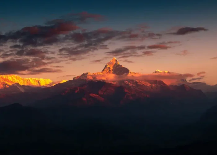 A breathtaking golden sunrise illuminating Mount Machapuchare and the Annapurna range with orange light, a popular view from Sarangkot.